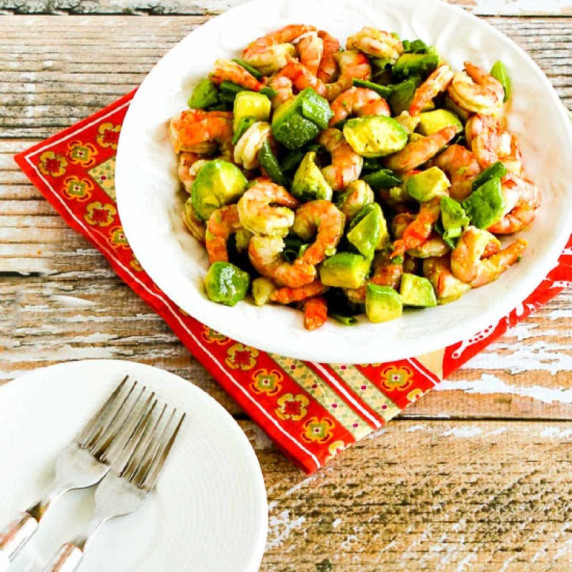 Shrimp and Avocado Salad shown on serving plate with napkin, plates, and forks.