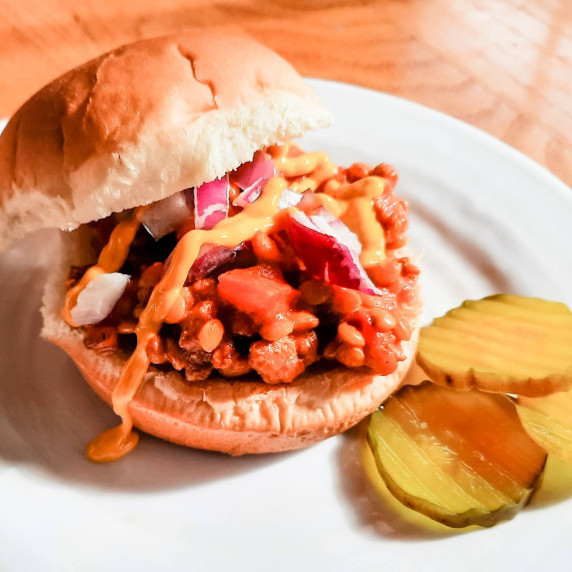 Turkey Lentil Sloppy Joes on a white plate next to a pile of pickles