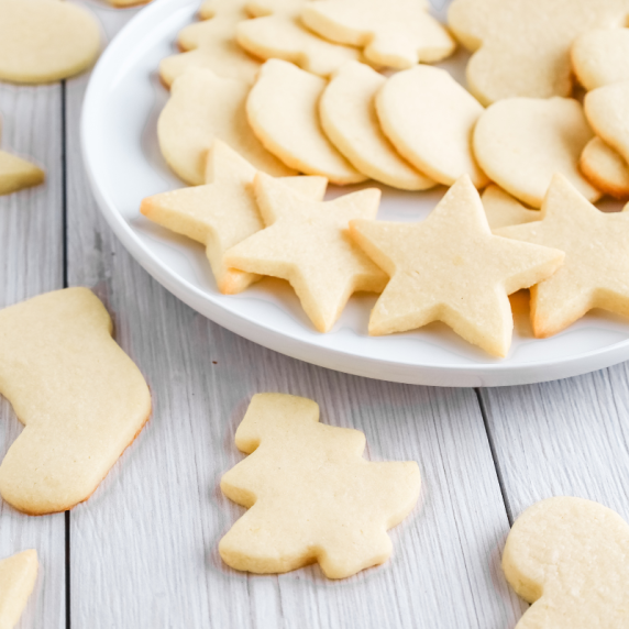 lemon cut out cookies on a white plate with a few on the table. 