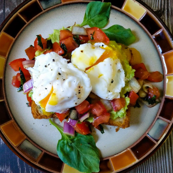 poached eggs over balsamic pico de gallo and mashed avocado on croissant bread