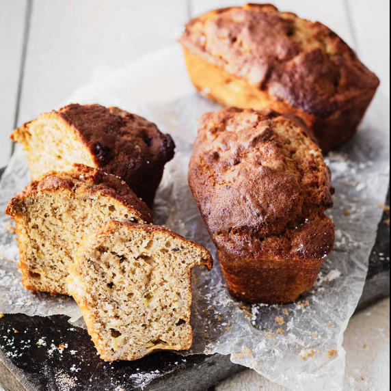 Sliced air fryer banana bread and two full loaves on crumpled wax paper.