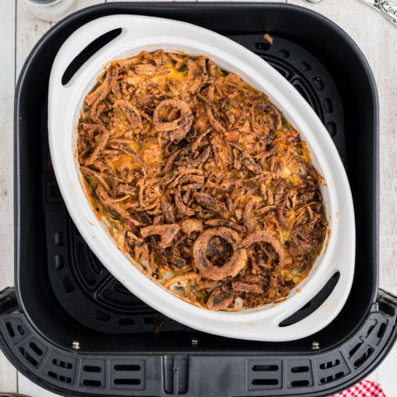 A casserole dish filled with a green bean casserole in an air fryer basket.