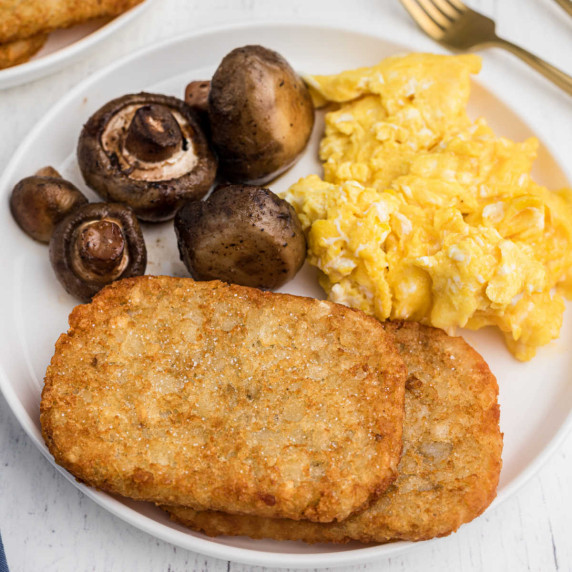two hash browns with scrambled eggs and mushrooms in the back