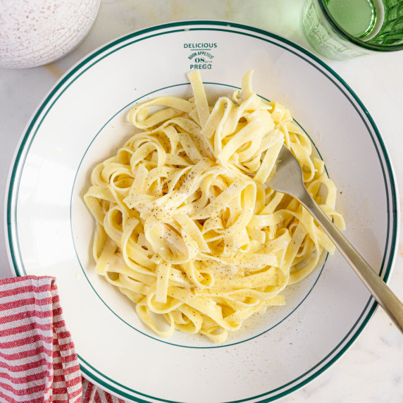 A plate of creamy Alfredo fettuccine pasta topped with freshly grated Parmesan and ready to serve.