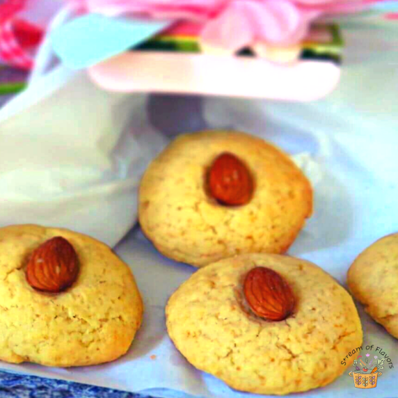 Almond biscuits garnished with raw almonds on paper with a decorative pink box