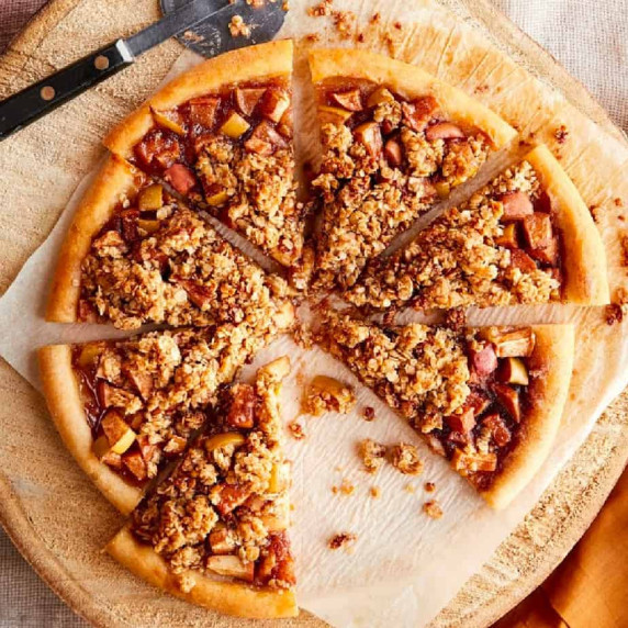 Close up of desert apple pizza with a piece missing.