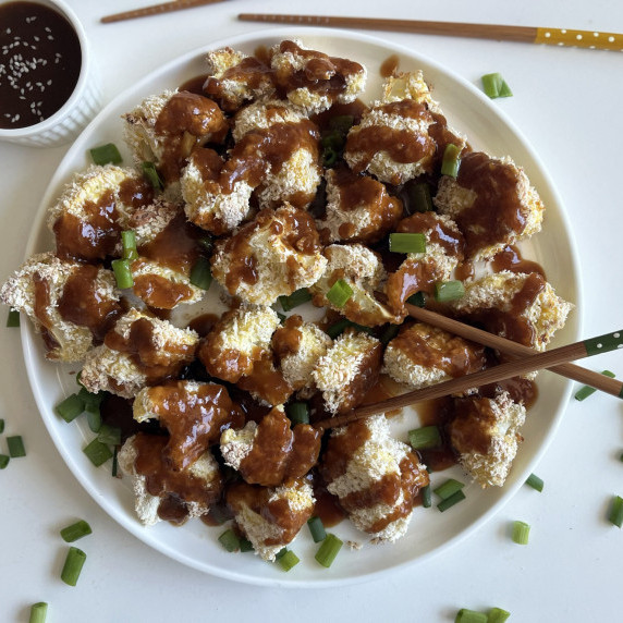 baked orange cauliflower with chopsticks on a white plate