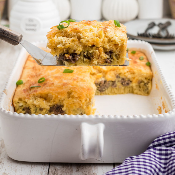 A slice of bisquick breakfast bake being lifted out of a casserole dish.