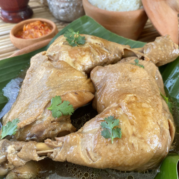 2 Thai boiled chicken thighs on top of a banana leaf.