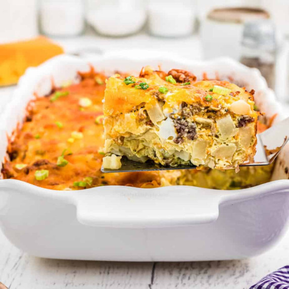 Slice of breakfast casserole being lifted from the pan with a spatula from the side.