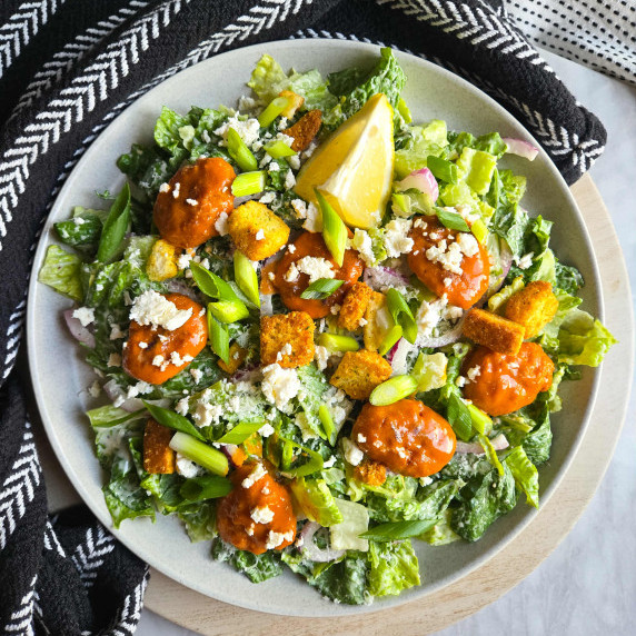 A colourful plate of salad with fiery red buffalo bites and loads of greens