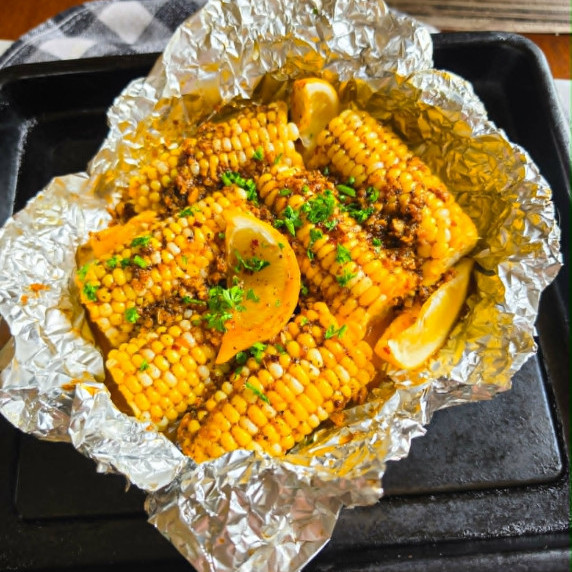 Golden cobs smothered in seasoned butter and green parsley.