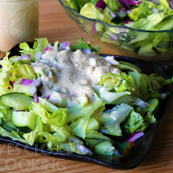 Caesar salad covered with dressing on a black plate