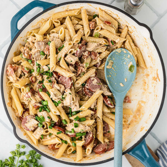 Overhead shot of a skillet full of chicken and sausage pasta with a spoon resting.