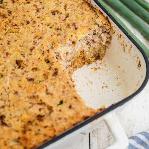 A pan of Cajun cornbread dressing with the corner gone.