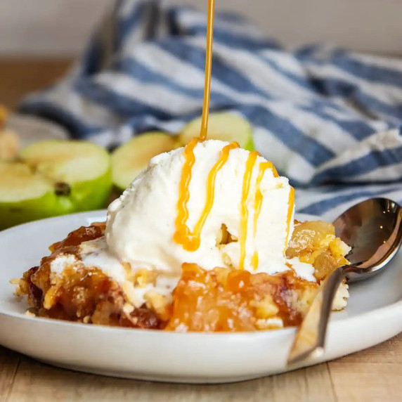 Photo of caramel being drizzled on top of ice cream with apple dumb cake.