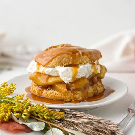 caramel apple shortcake on a white plate with yellow flowers nearby