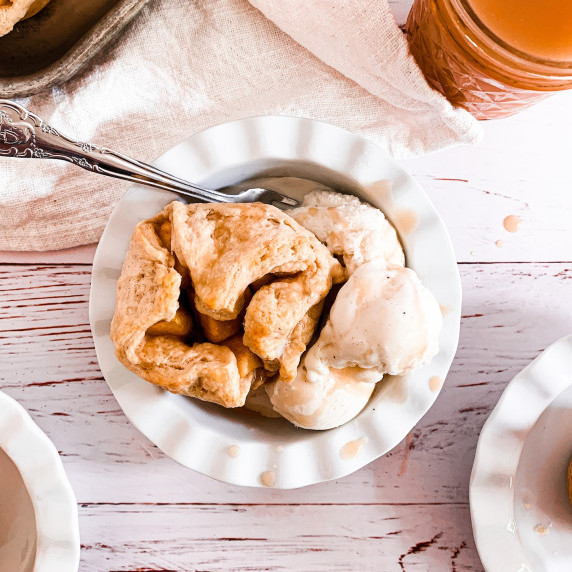 chai masala apple dumpling with vanilla bean ice cream and caramel sauce in a white dish
