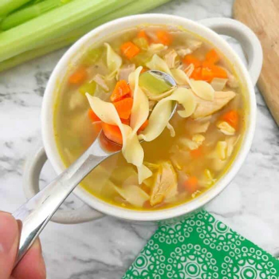 A bowl of chicken noodle soup from above.
