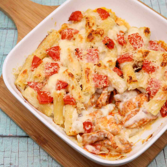 chicken pasta bake in a white bowl on a chopping board