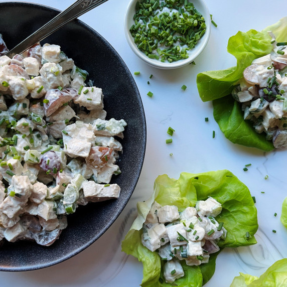 Chicken salad in a gray bowl next to bibb lettuce filled stuffed with chicken salad.
