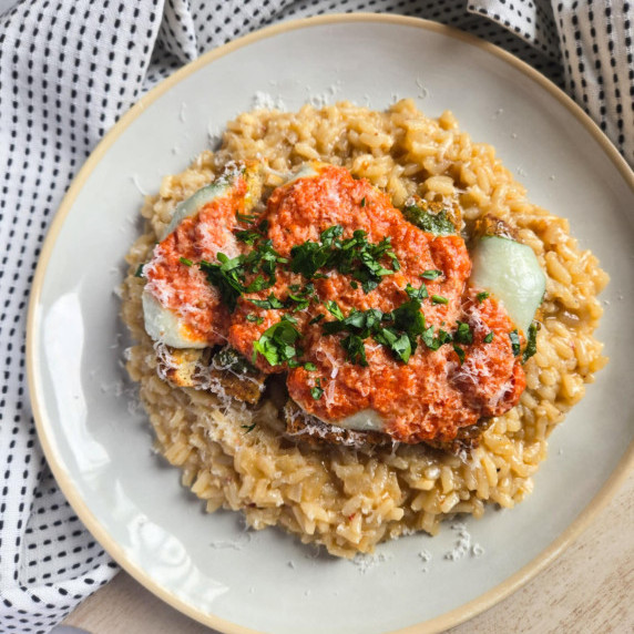 Creamy risotto topped with red vodka sauced chik'n and pops of green