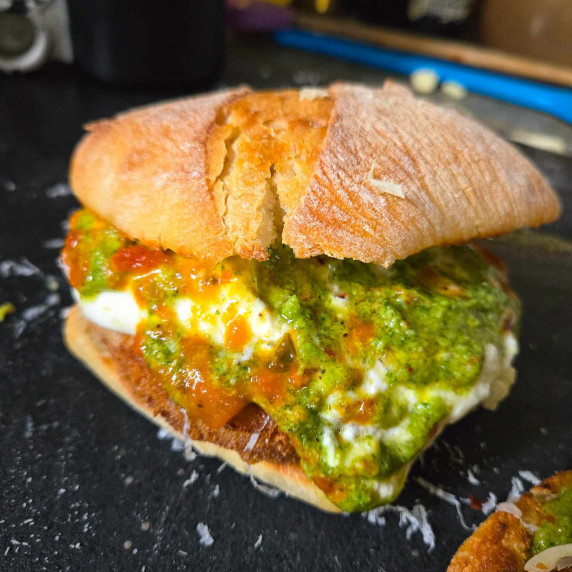 Golden ciabatta stuffed with bright green pesto, red sauce, and white burrata cheese.