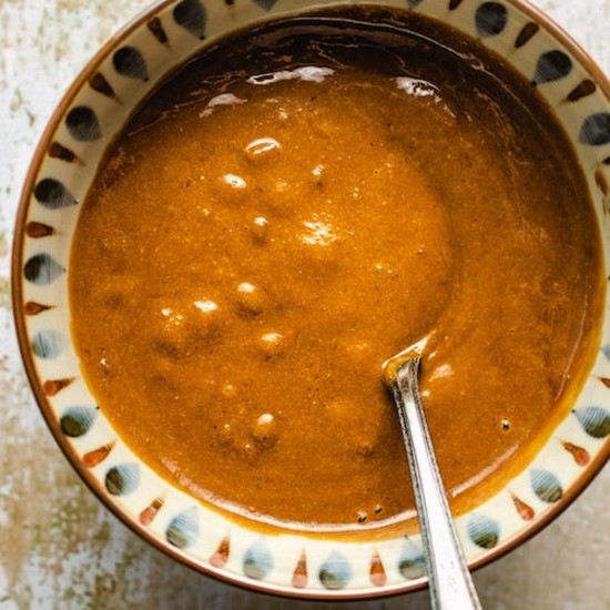 Hoisin sauce in an earthenware bowl with a stainless steel spoon