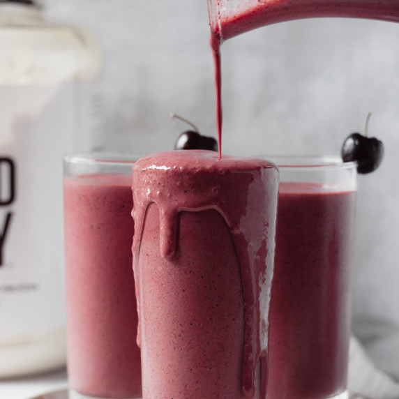 Chocolate cherry smoothie poured in a glass with a cherry on top