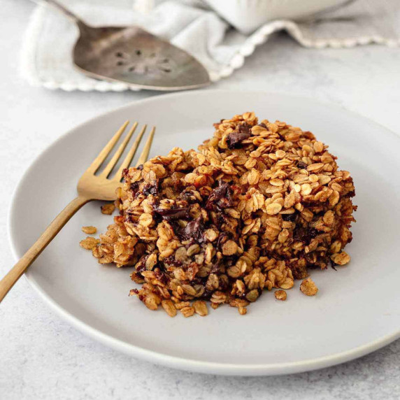 Serving of chocolate chip baked oatmeal on a grey plate with a gold fork.