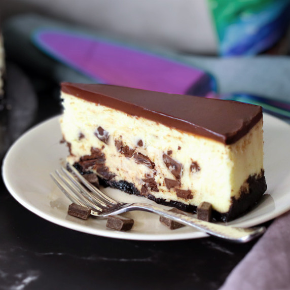 A slice of Chocolate Chunk Cheesecake on a white plate