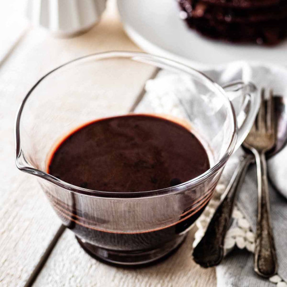 Chocolate pancake syrup in a small glass pitcher.