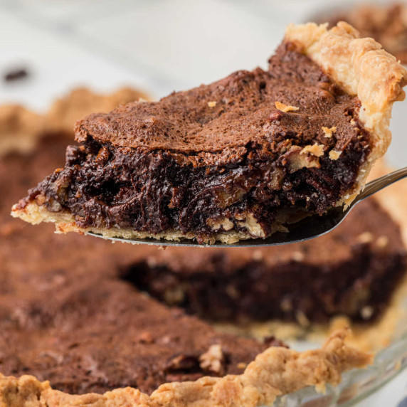 A slice of chocolate pecan pie being lifted out of a pie dish.