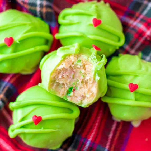 View of a green Grinch golden Oreo balls stacked from above with the top truffle missing a bite.