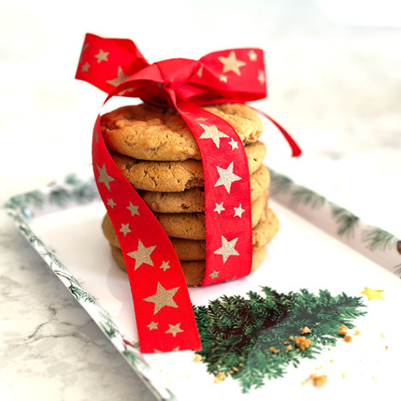 Six Biscoff Butter Cookies are stacked atop one another, adorned with a festive bow.