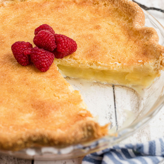 Close up of a pie dish with a buttermilk pie recipe in it, with a slice gone.