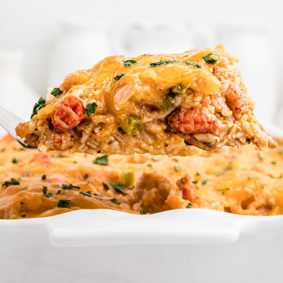 A scoop of crawfish casserole being lifted out of dish.