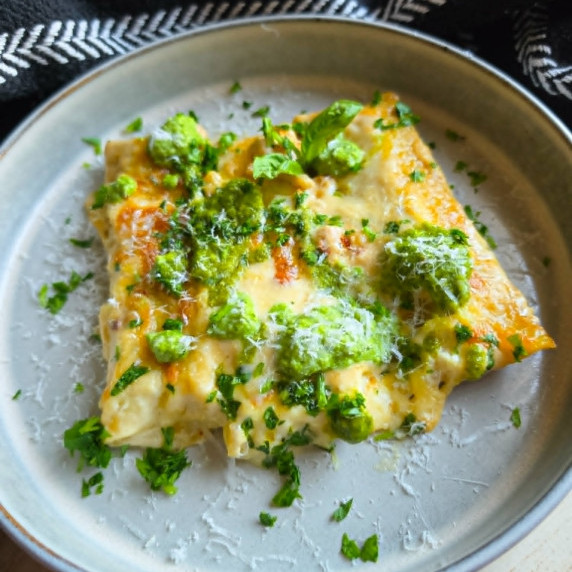 Golden cannelloni with dollops of green pesto and herbs.