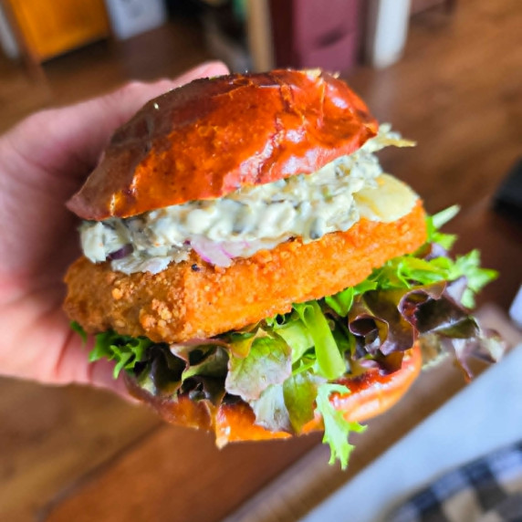 Golden pretzel bun with creamy spinach dip, green lettuce and golden chik'n