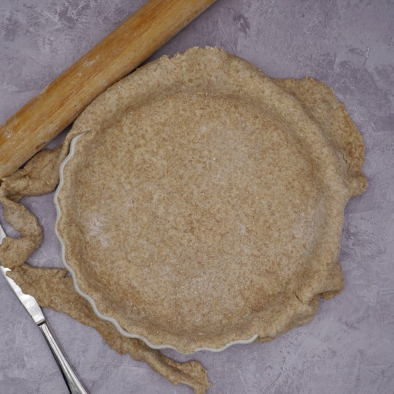 Partly trimmed pastry in a quiche dish. 