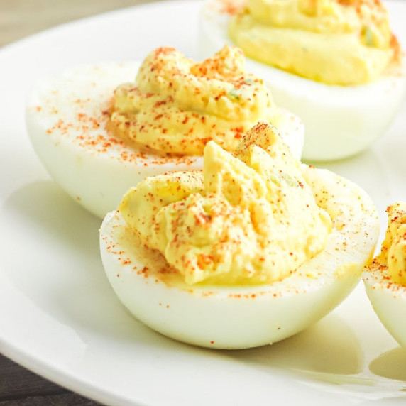 Super close up of four deviled eggs on a white plate