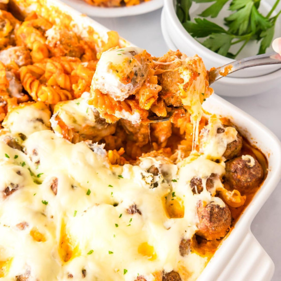 A dump and bake meatball casserole in a pan being served with a spoon.