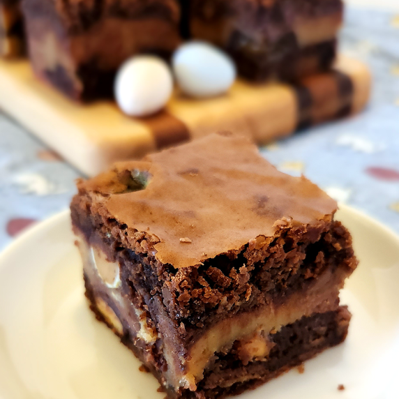 Easter candy brownie on a plate with more brownies in the background against an Easter pattern cloth