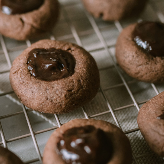 small chocolate raspberry thumbprint christmas cookies on a cooling rack