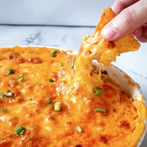 Buffalo Chicken Dip No Cream Cheese bite being taken with a nacho.