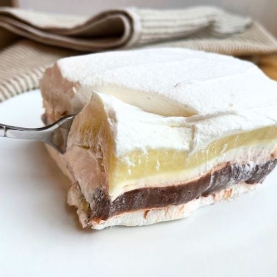 A piece of chocolate delight on a white plate with a fork taking a bite from it.