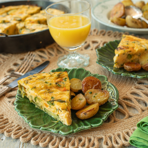 A slice of frittata primavera on a green plate.
