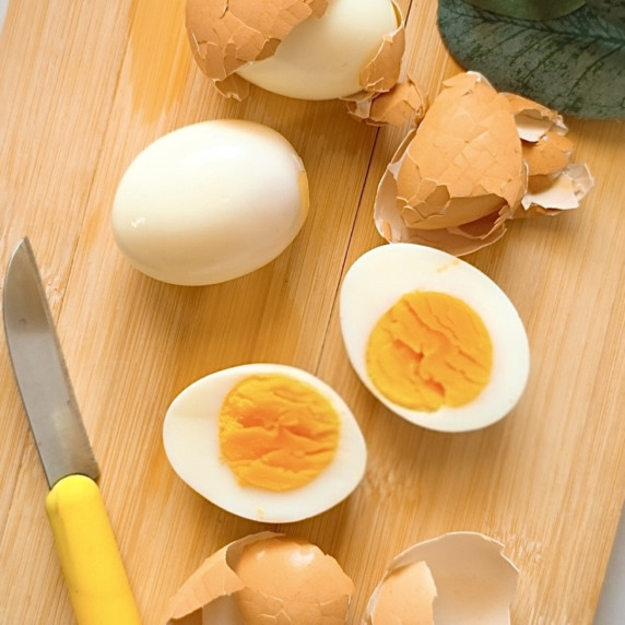 Boiled eggs cut over a wooden cutting board.