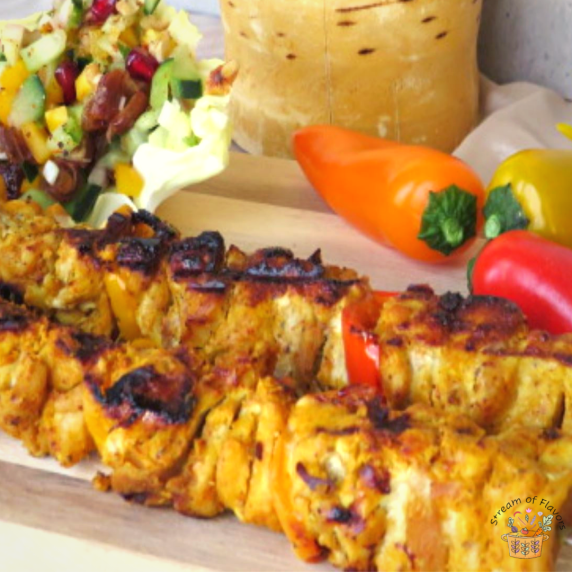 Egyptian chicken kebabs on skewers with a salad and mini bell peppers and North African utensil