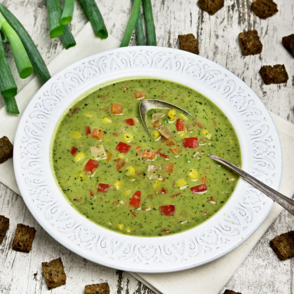 Creamy green pea soup with crispy bacon and fresh summer vegetables
